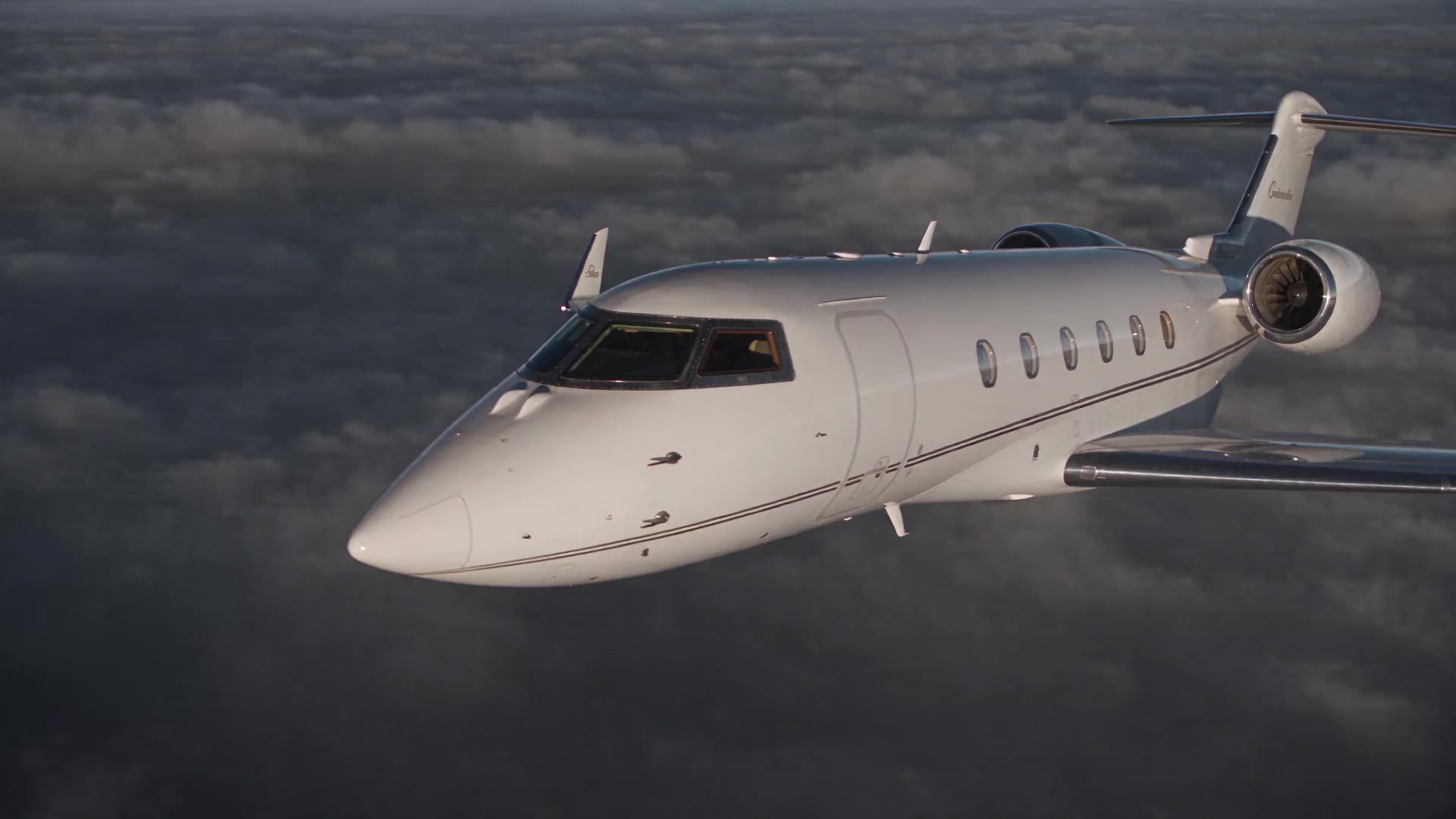 A private jet flying above dark silver cloud tops